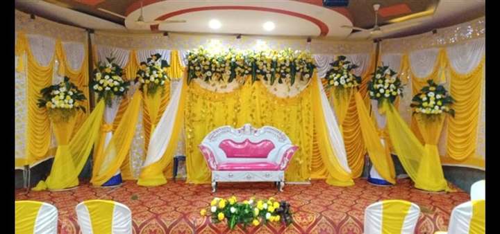 Nikah stage with yellow and white drape swags and floral table centrepiece