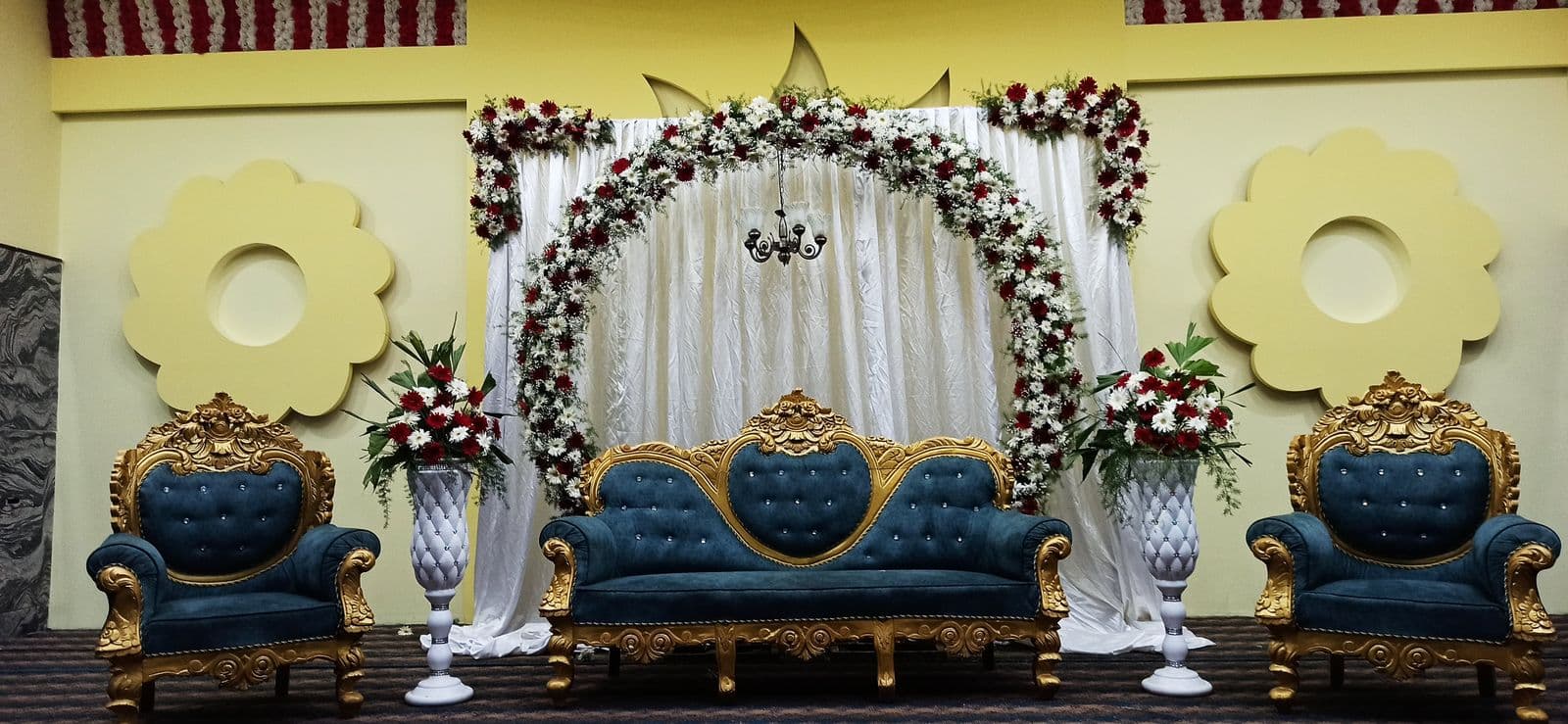 Stage with floral arch and royal blue sofas for the couple and family
