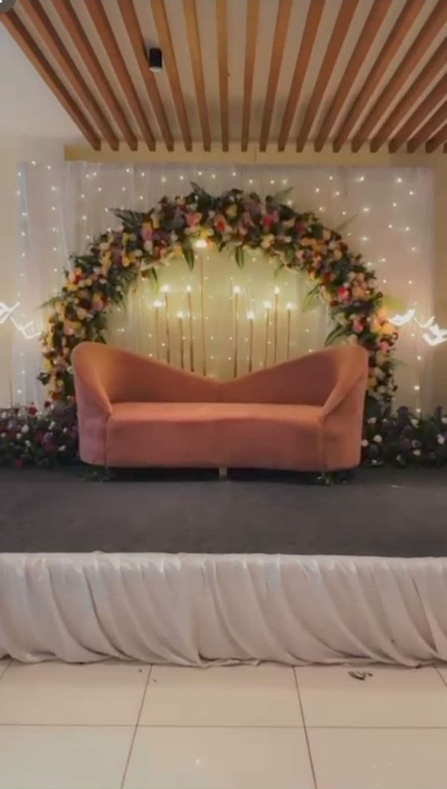 Floral ring backdrop with fairy lights and a peach sofa