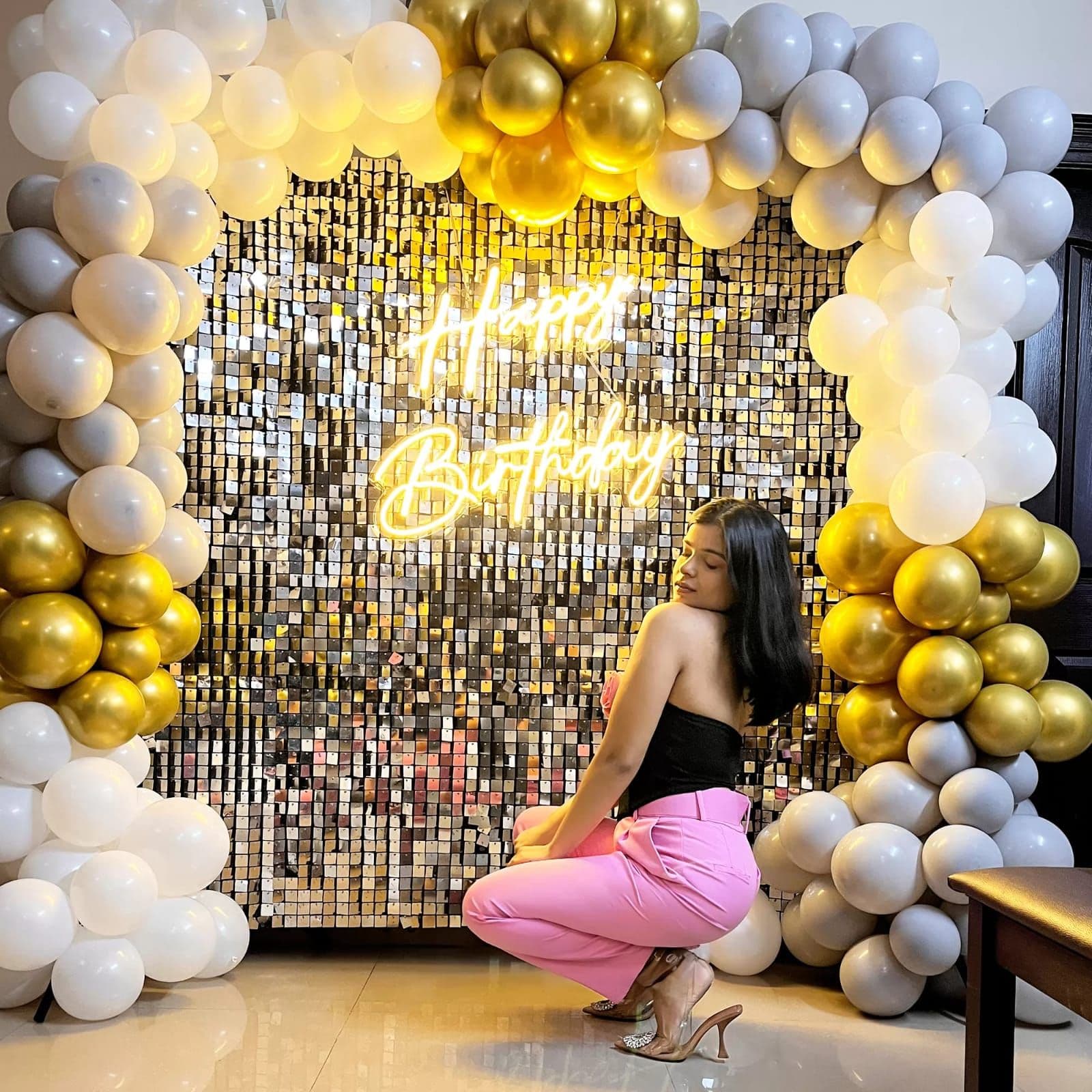 Gold sequin wall framed by gold, white and silver balloon garland for a birthday