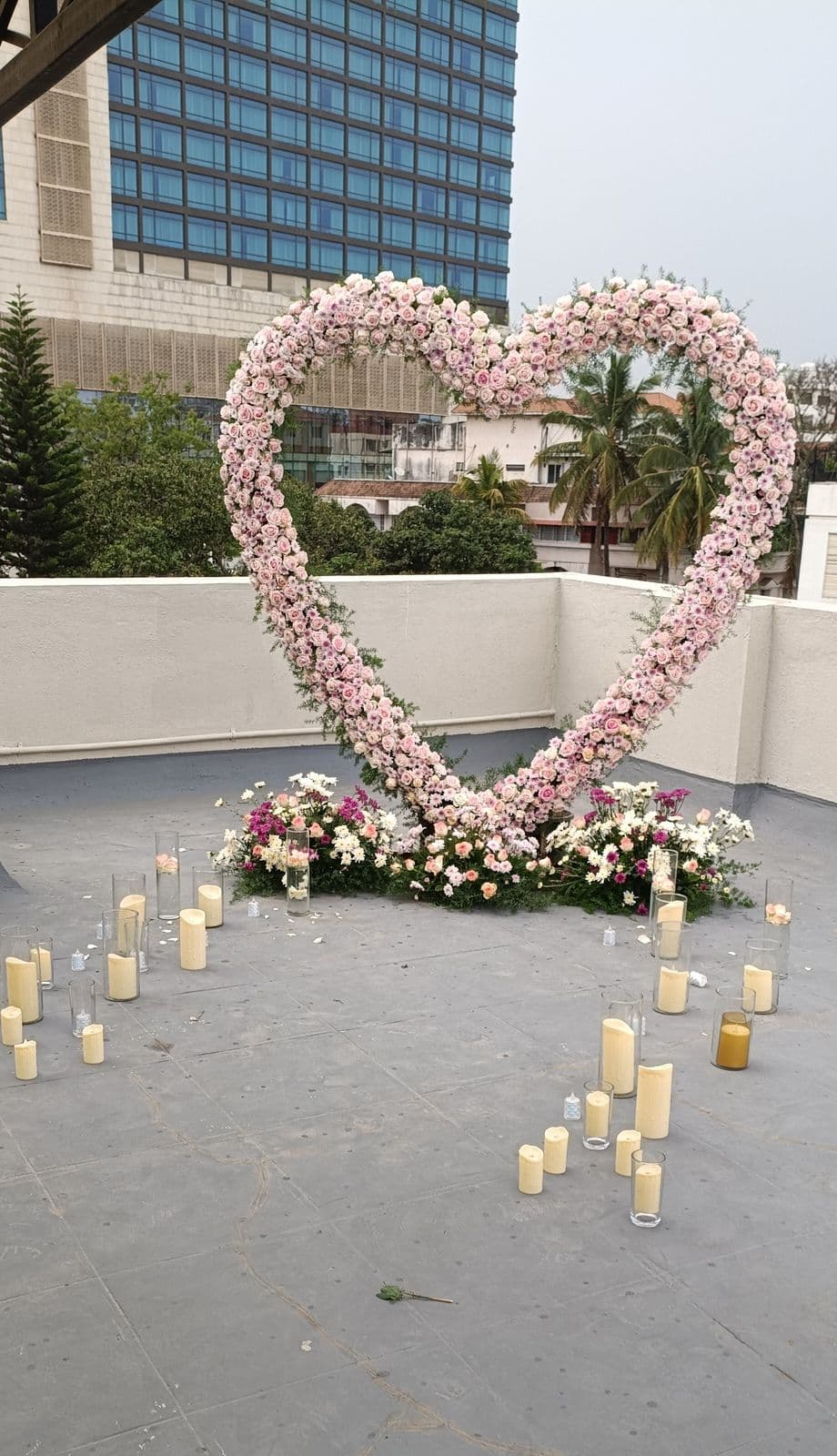 Heart-shaped pink rose arch with candles for a rooftop proposal