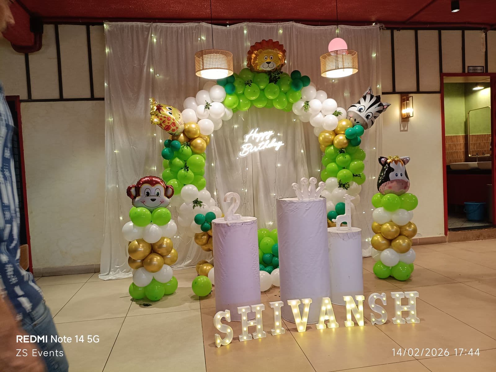 Jungle-themed birthday balloon arch with animal props and name letters