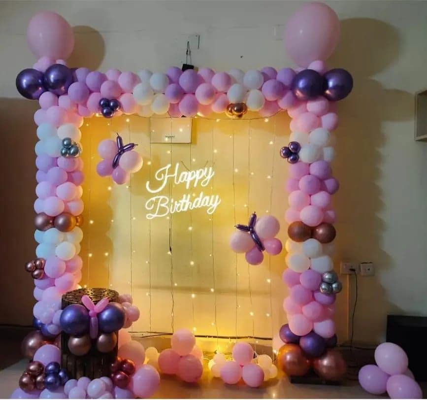 Lilac and plum balloon frame with butterflies and warm fairy lights for a birthday