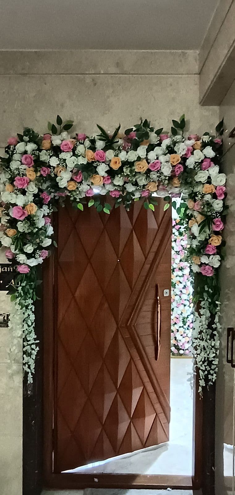Home main door framed with pink and white roses and hanging greenery
