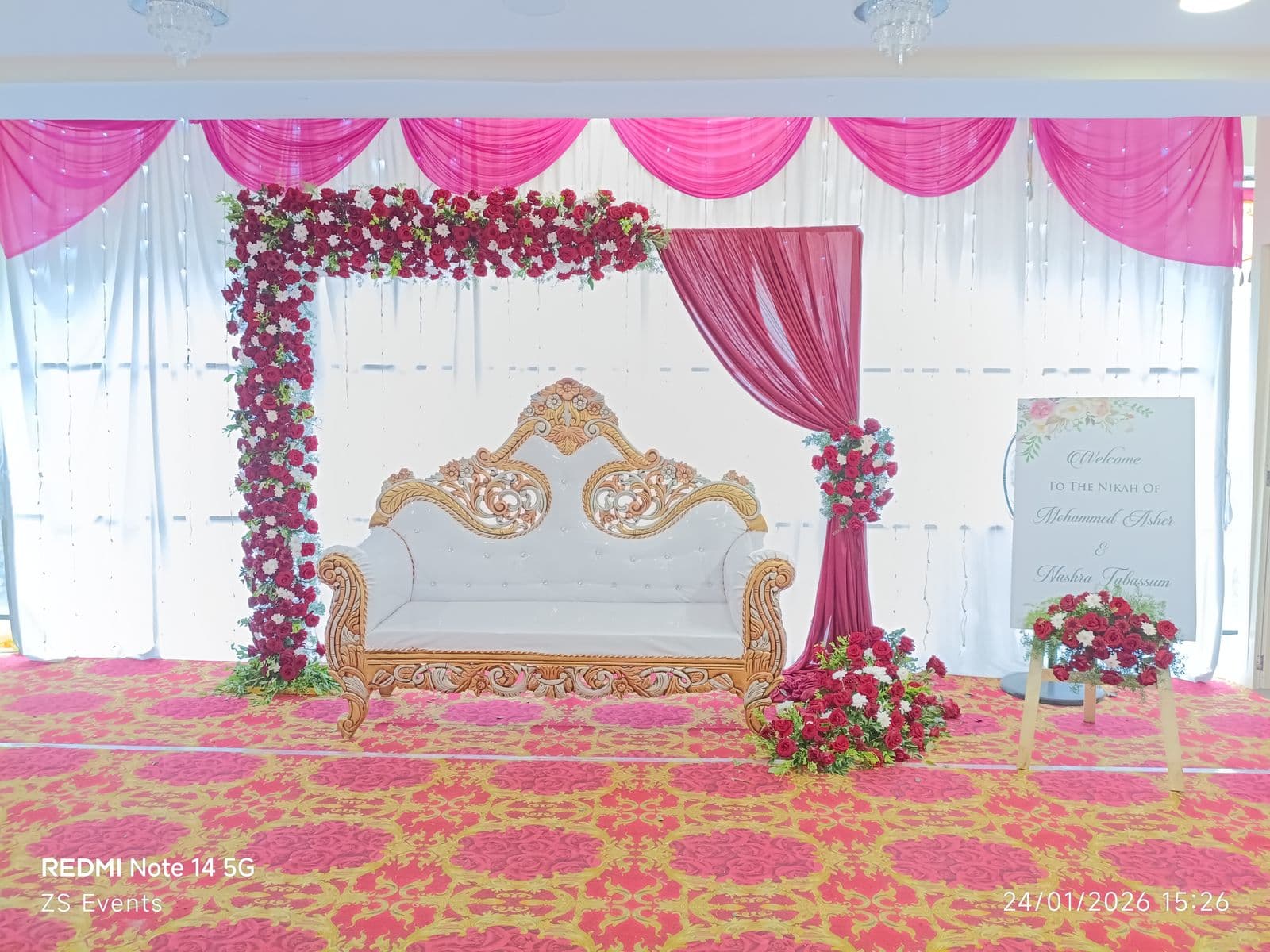 Pink and white drape stage with floral corner and white sofa