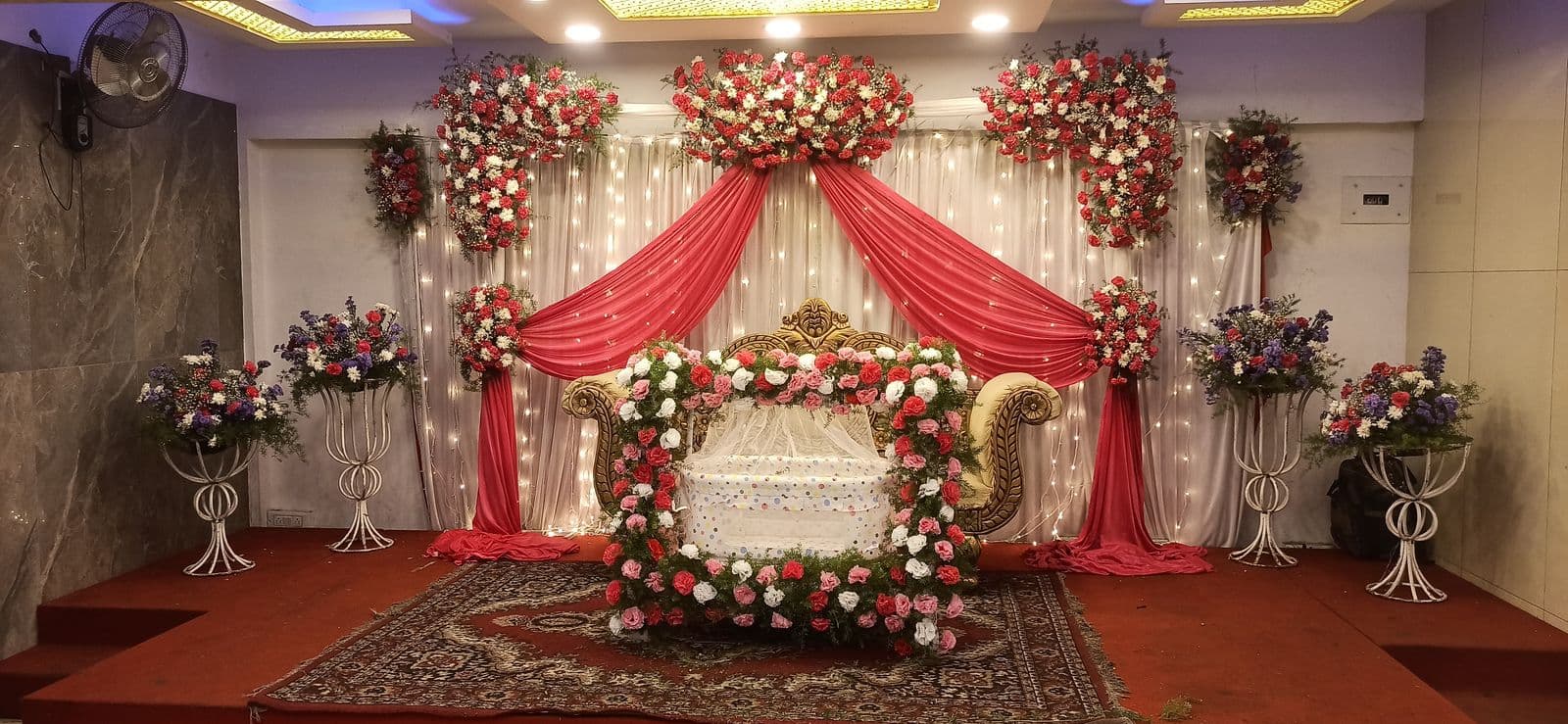 Red and white drape stage with gold chaise and floral stands