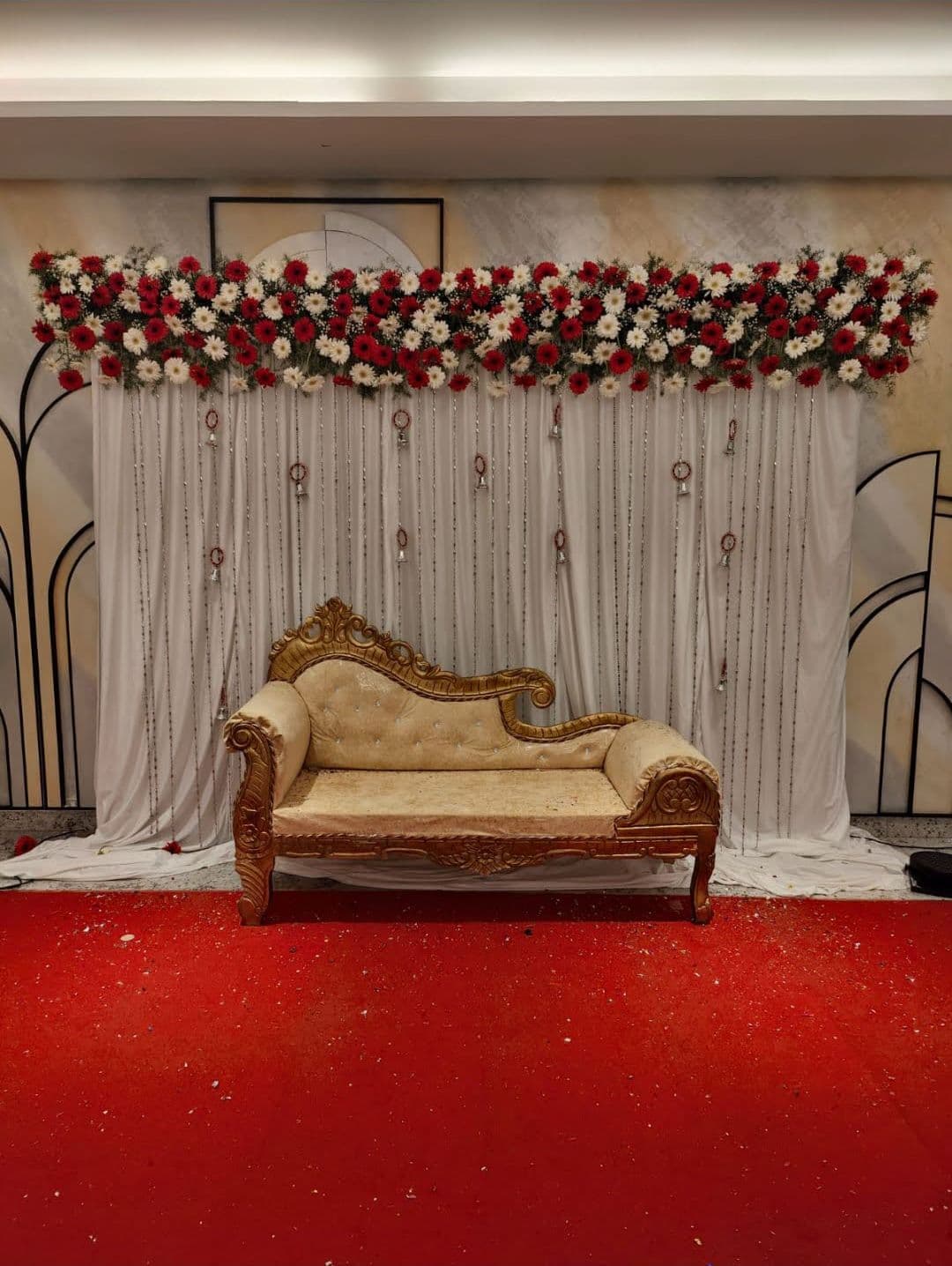 White floral stage with a gold chaise on a red carpet