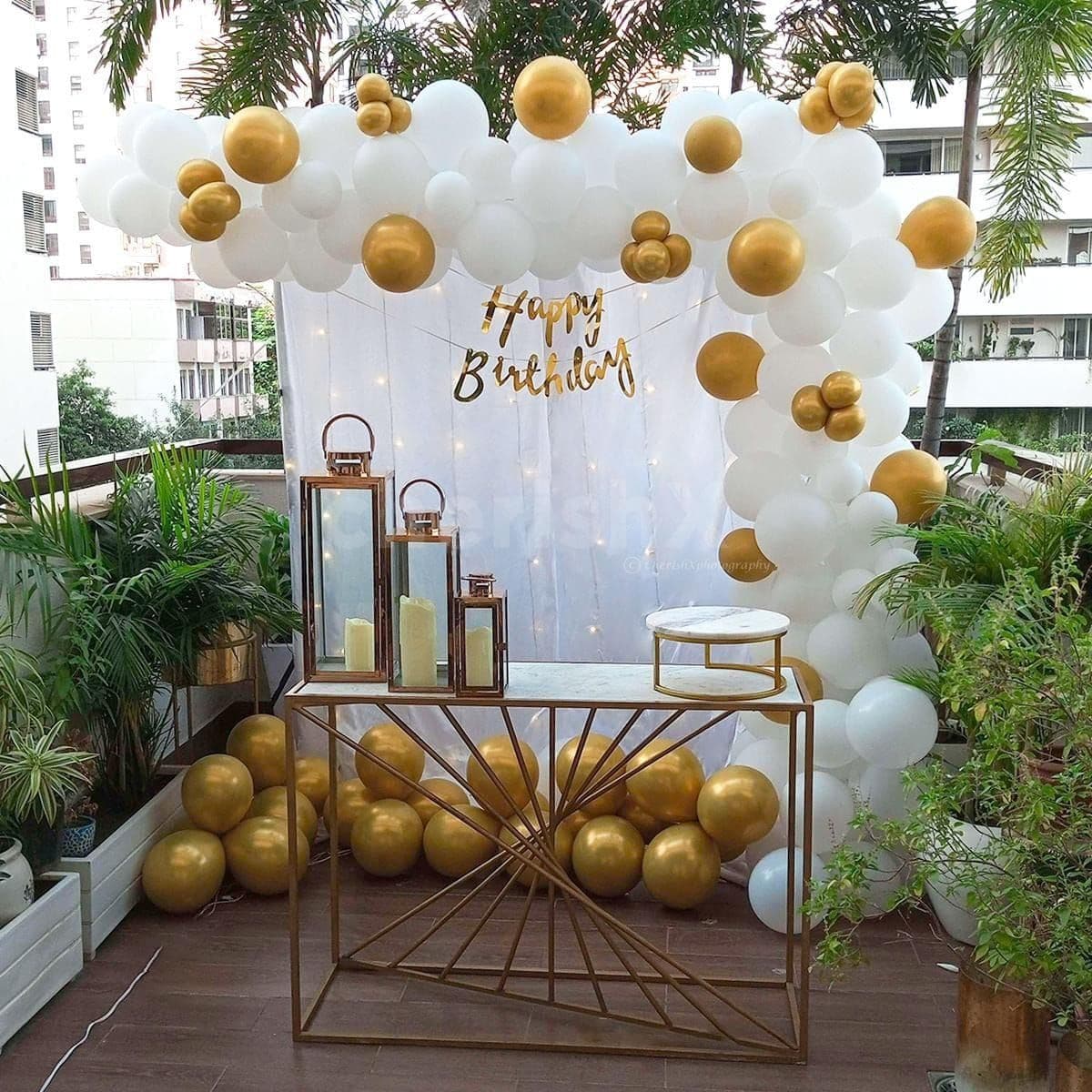 White and gold balloon backdrop with Happy Birthday sign on a terrace