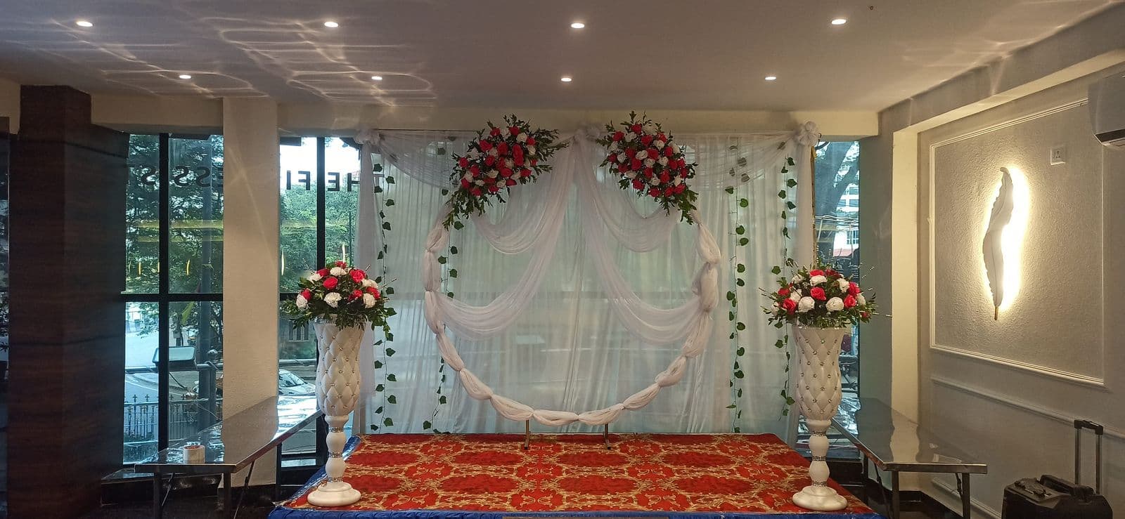 White hall stage with floral stands and drapes