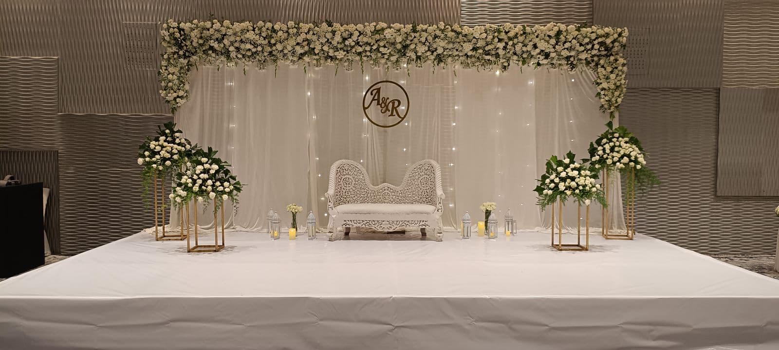 White engagement stage with couple monogram and floral stands