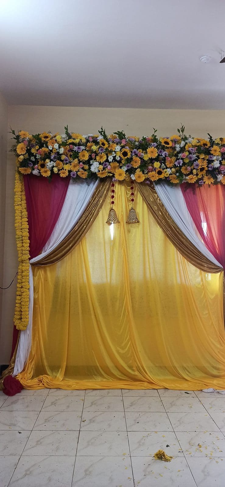 Yellow and maroon drape haldi backdrop with marigold strands