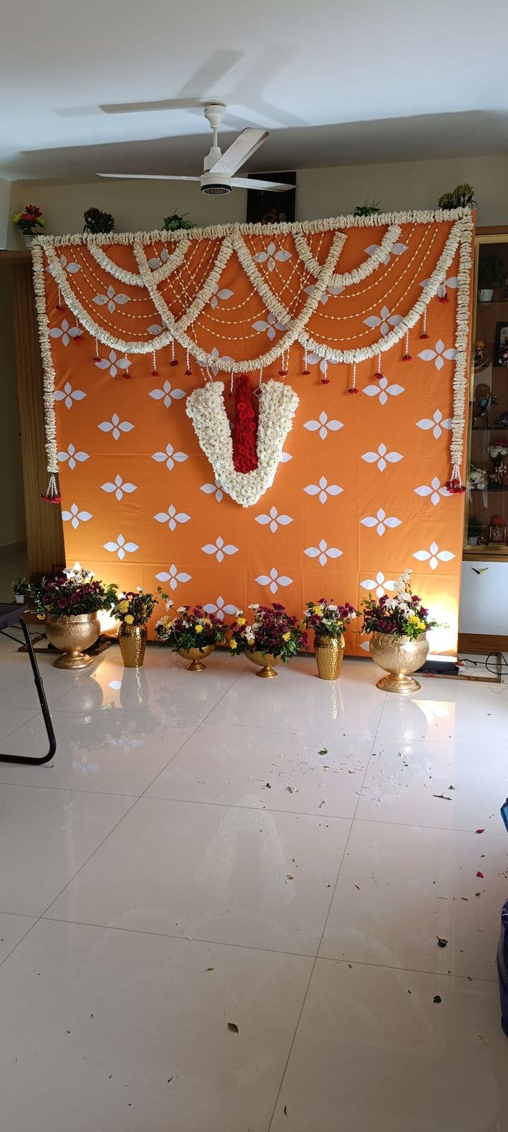 Orange pooja backdrop with white flower garland